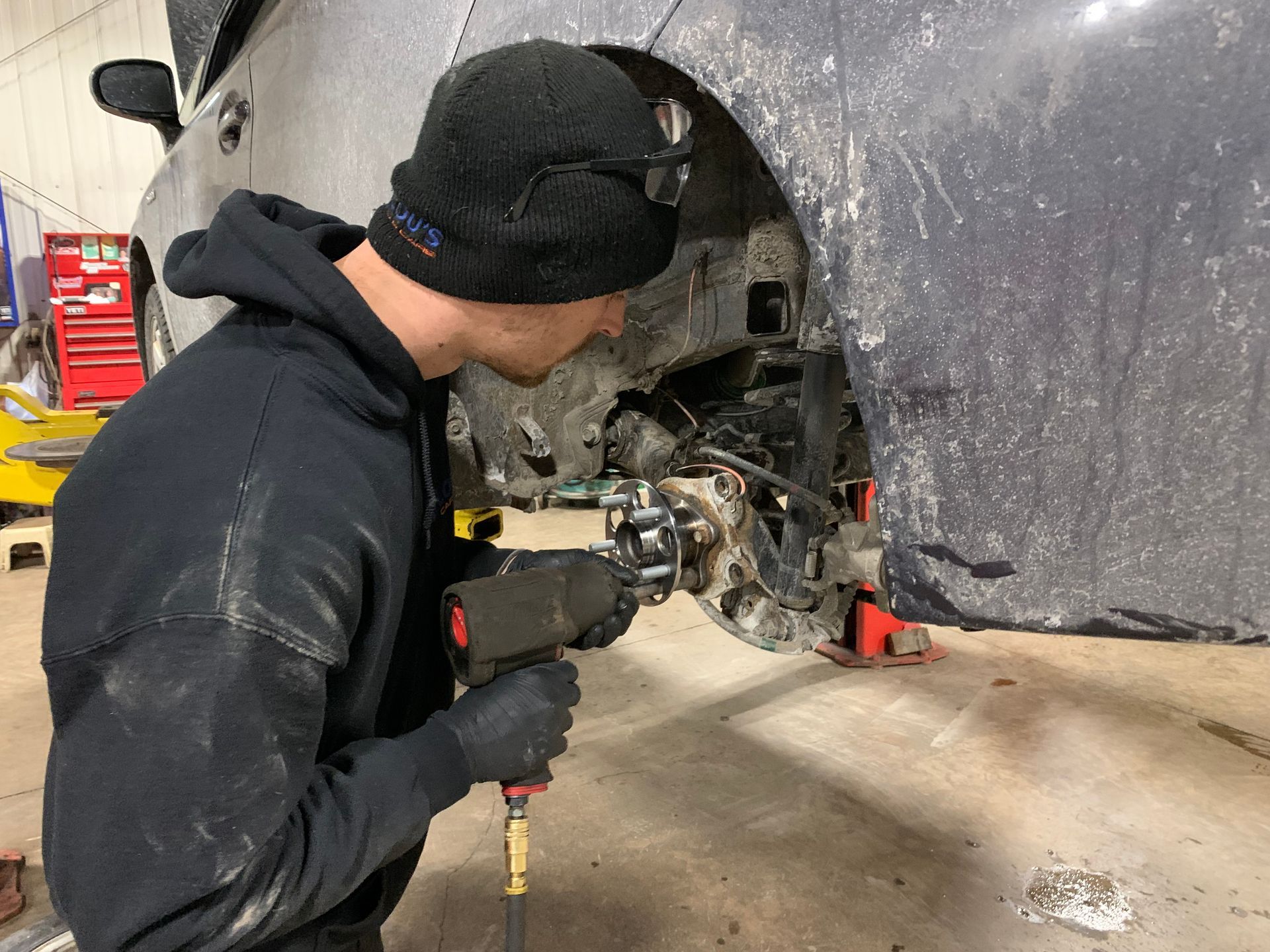 A man is working on a car in a garage. | Lou's Car Care Center, Inc.