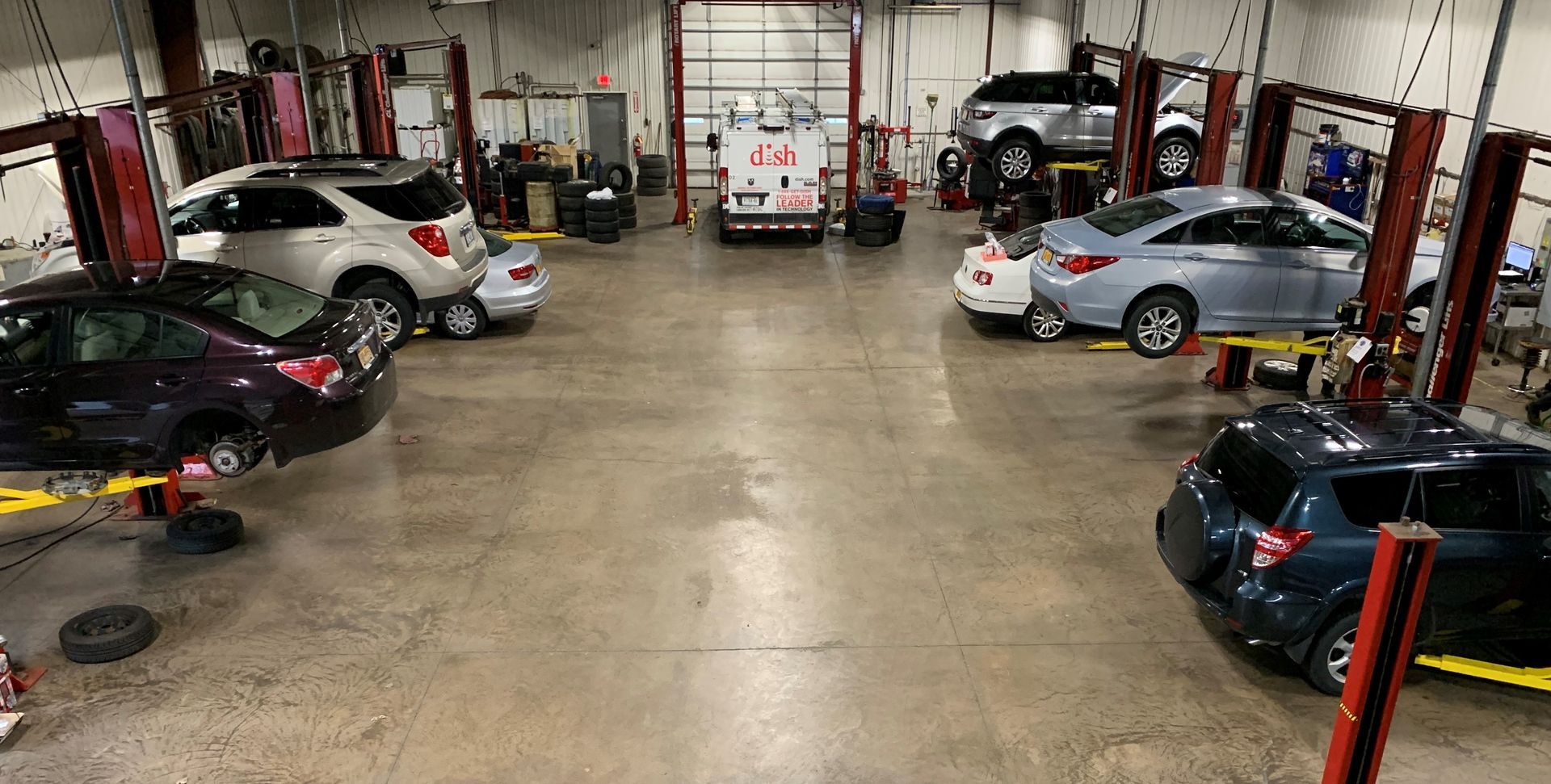 A lot of cars are sitting on lifts in a garage.  | Lou's Car Care Center, Inc.