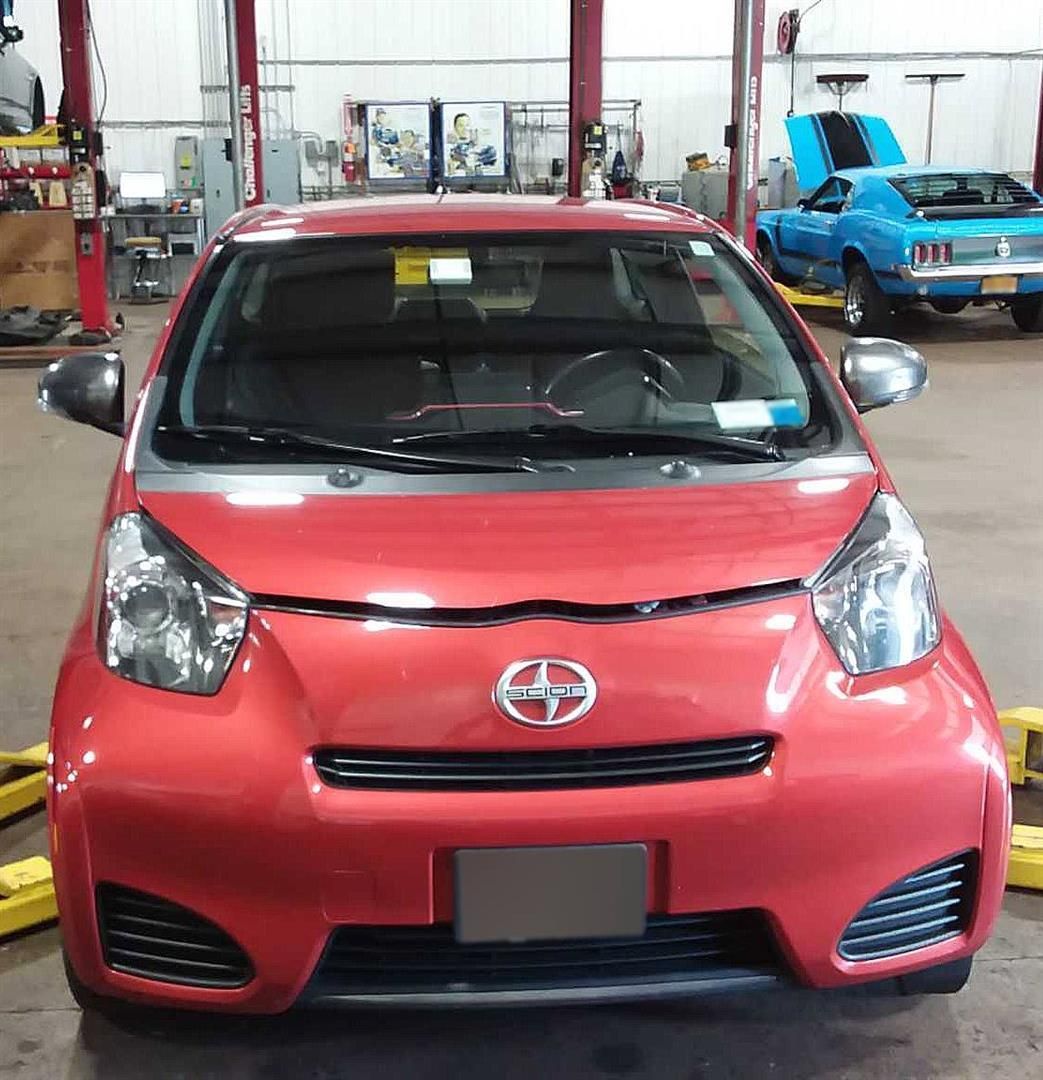 A red scion car is parked in a garage | Lou's Car Care Center, Inc.