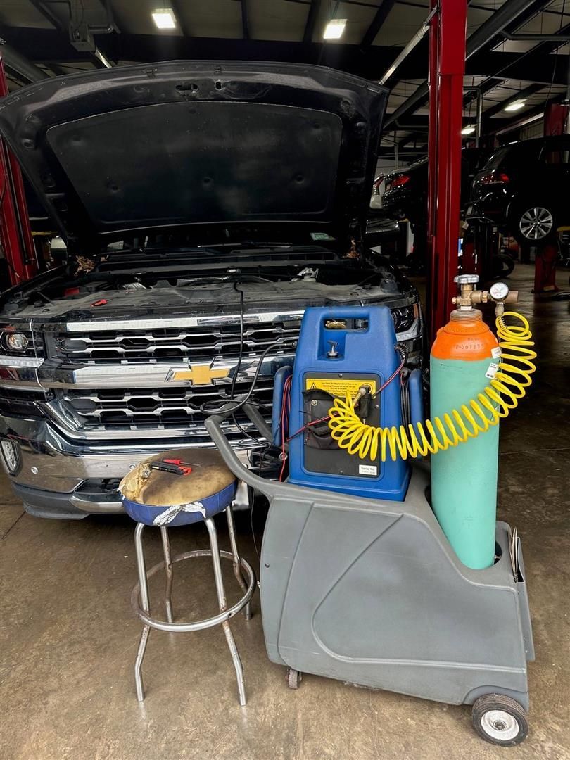 A truck is being worked on in a garage with the hood open. | Lou's Car Care Center, Inc.