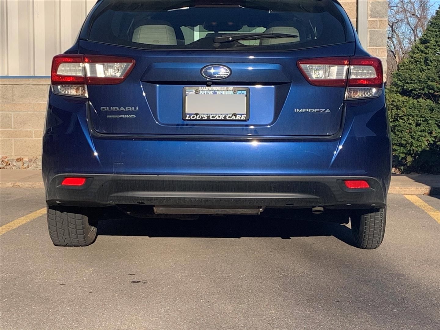 A blue subaru is parked in a parking lot  | Lou's Car Care Center Inc.