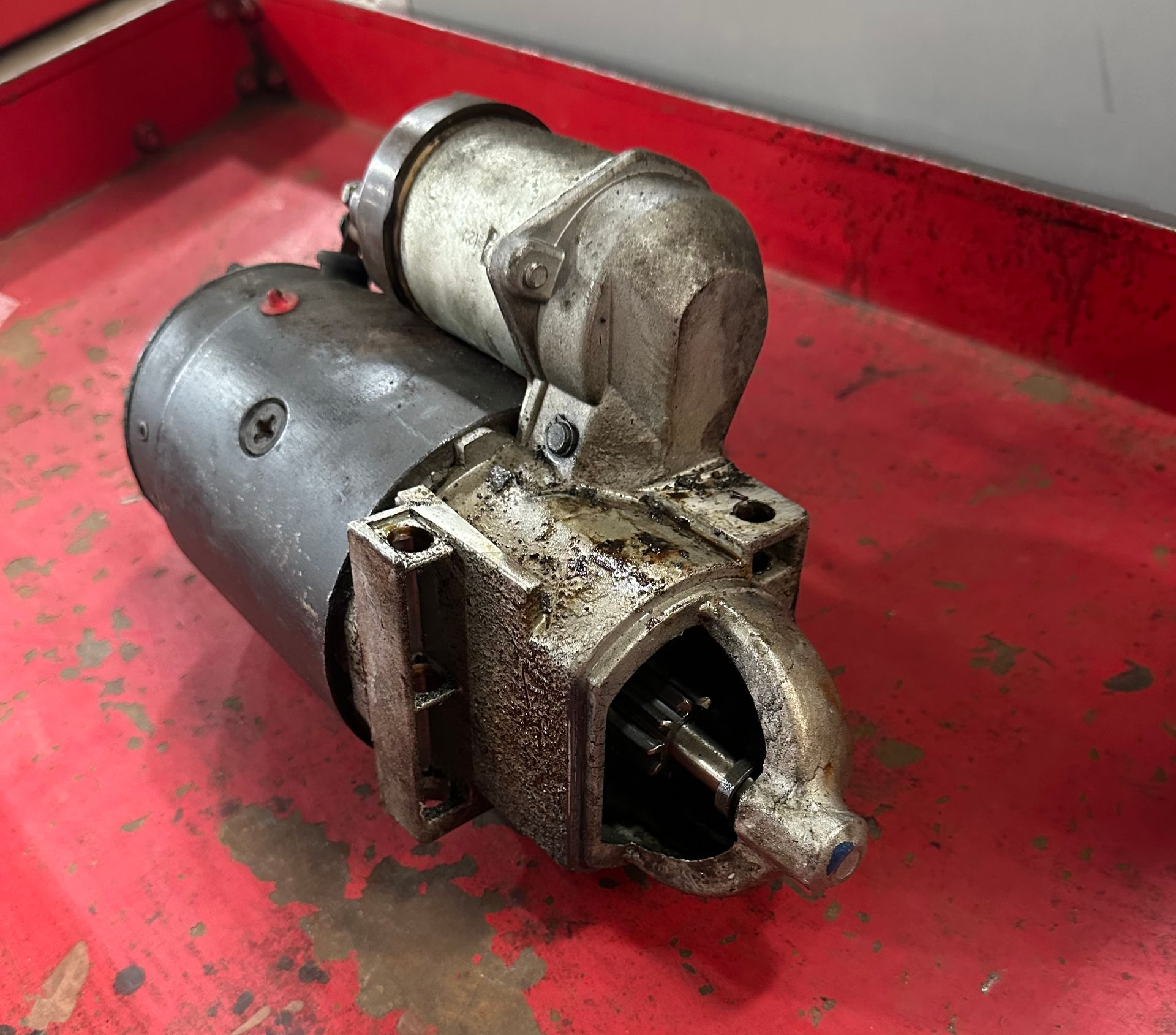 A starter motor on a red cart in the shop.