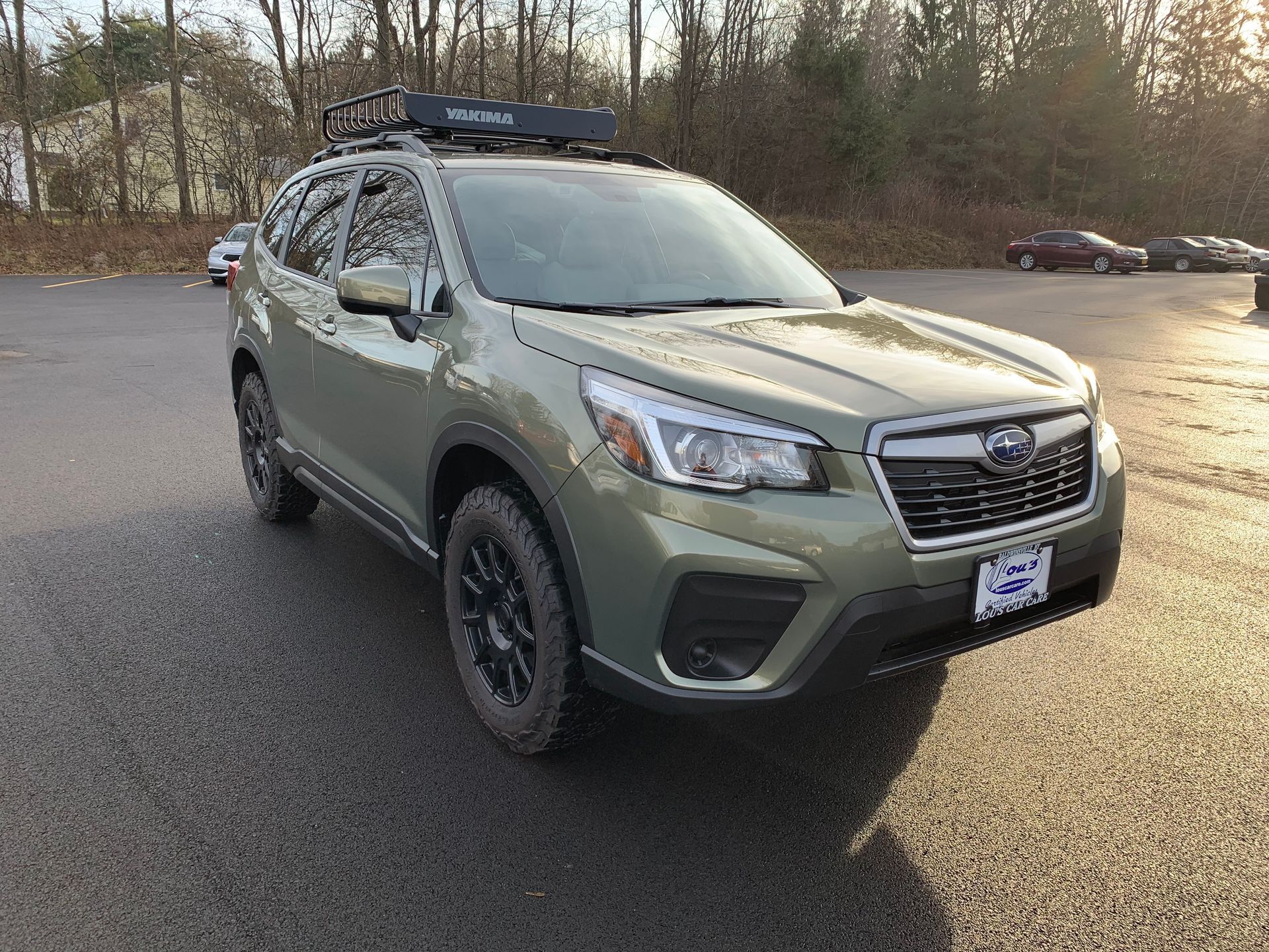 A green subaru forester with a roof rack is parked in a parking lot. | Lou's Car Care Center, Inc.