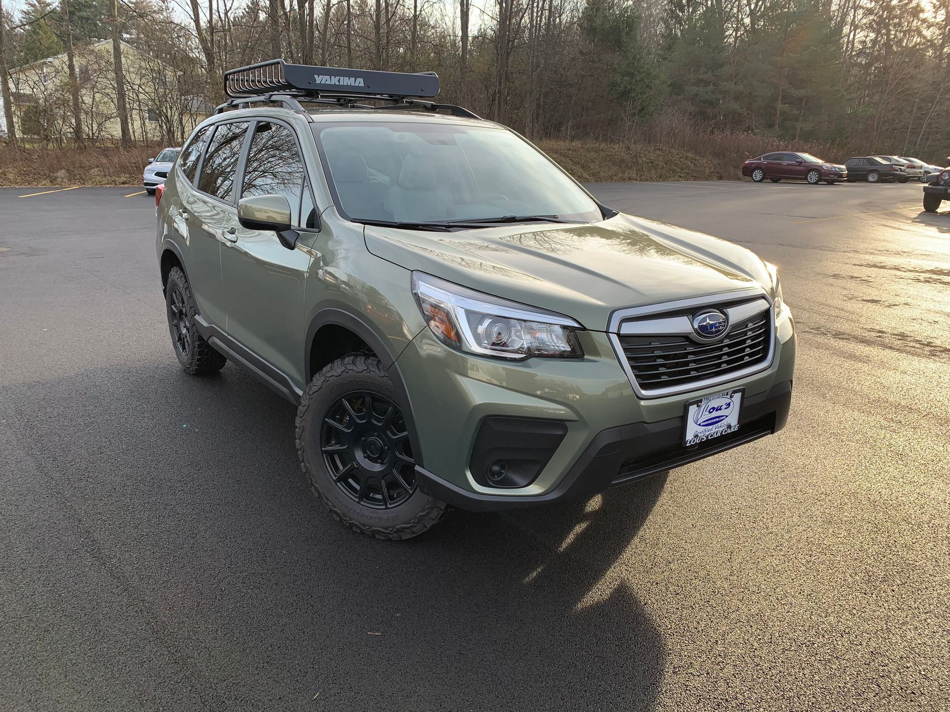 A green subaru forester with a roof rack is parked in a parking lot.  | Lou's Car Care Center, Inc.