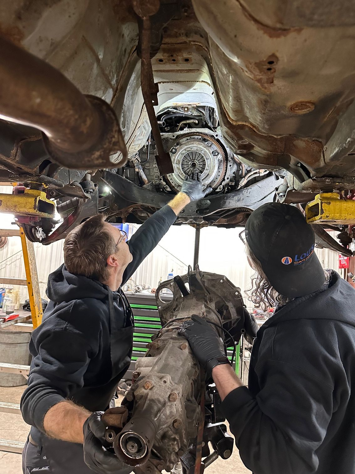 Auto Technician adding oil to an engine in a blue car. Lou's Car Care Center, Inc.