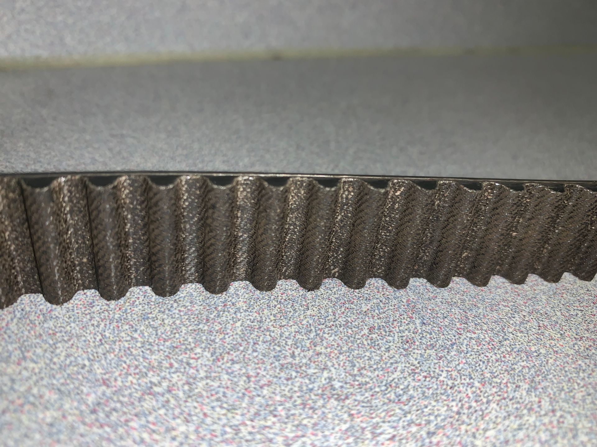 A close up of a belt on a carpet on a table. | Lou's Car Care Center Inc.