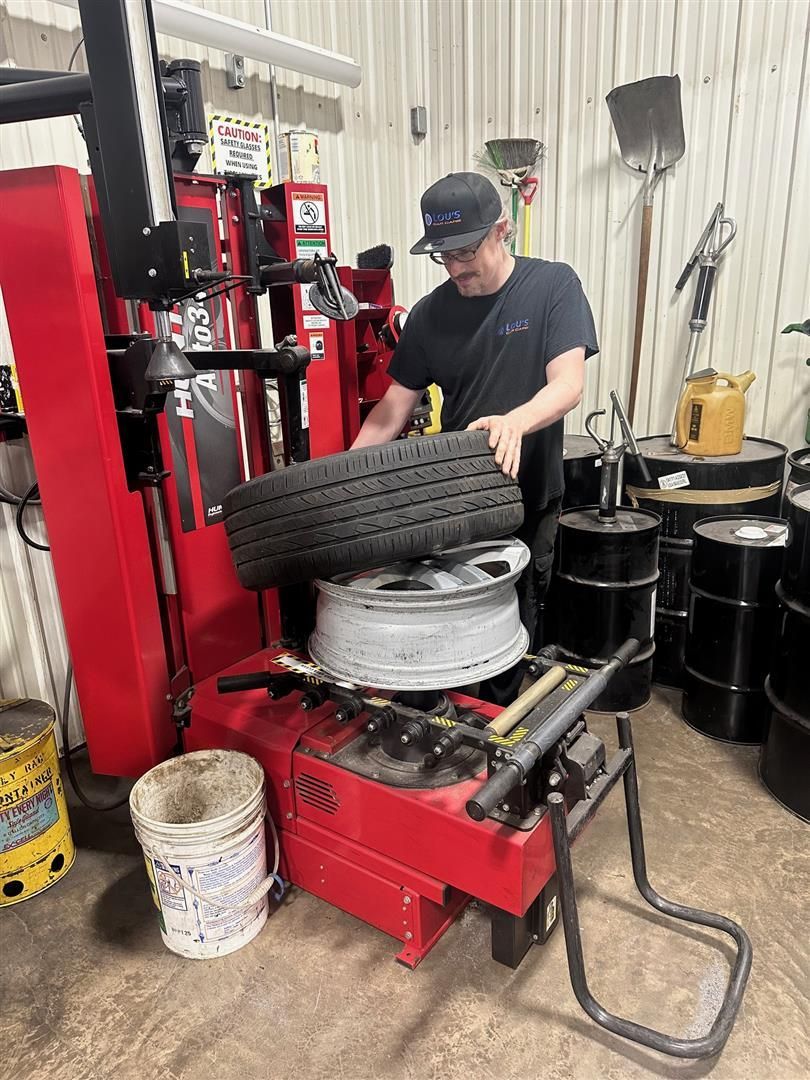 A man is changing a tire on a machine in a garage.  | Lou's Car Care Center, Inc.