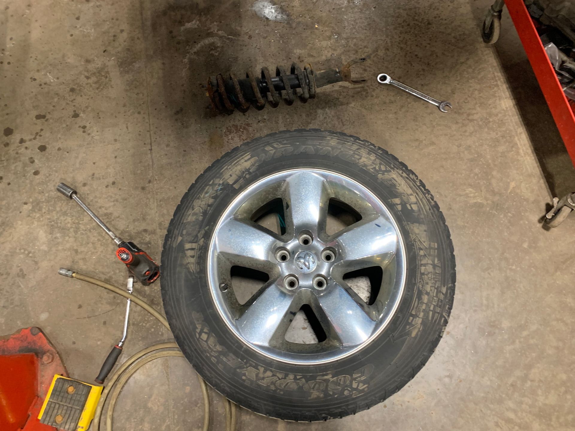 A tire is sitting on the ground next to a shock absorber. | Lou's Car Care