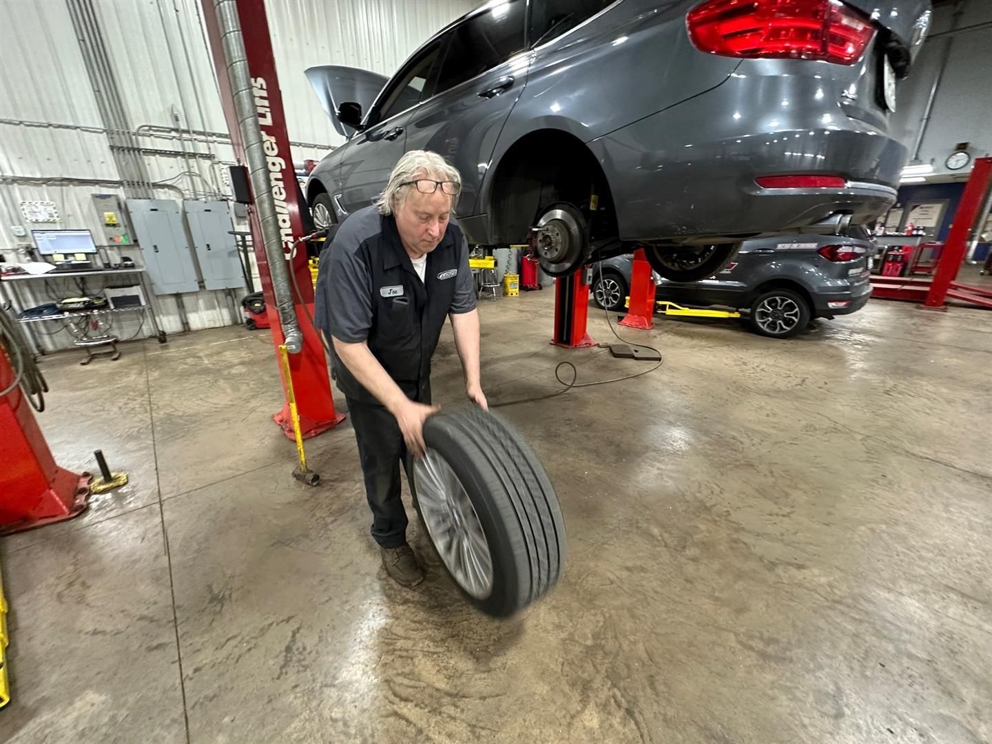 A man is changing a tire in a garage. | Lou's Car Care Center, Inc.