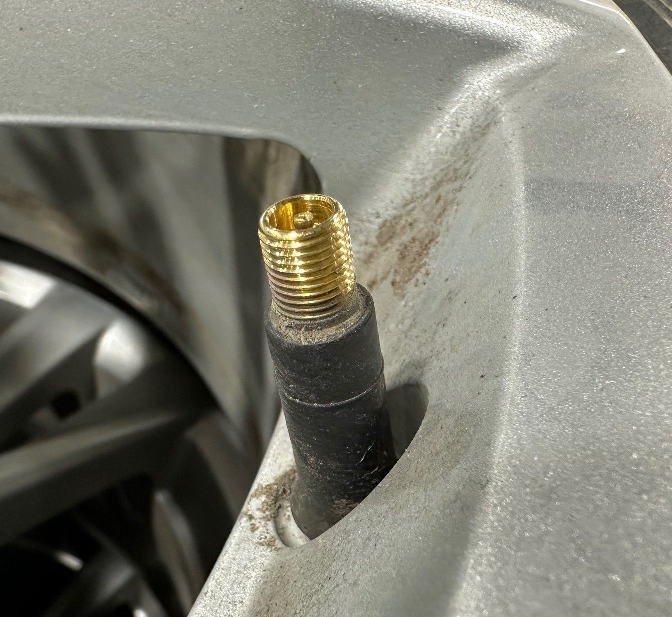 Black valve stem on vehicle wheel without the cap.