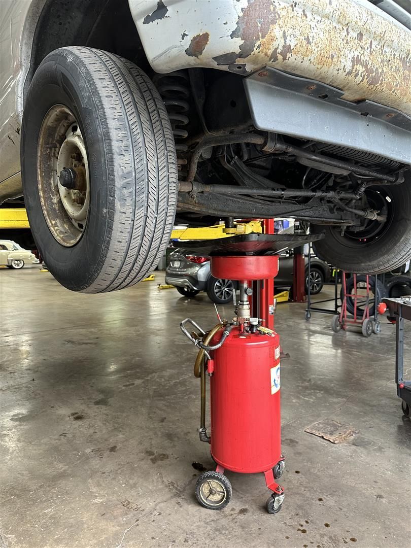 A car is sitting on a lift in a garage.  | Lou's Car Care Center, Inc.