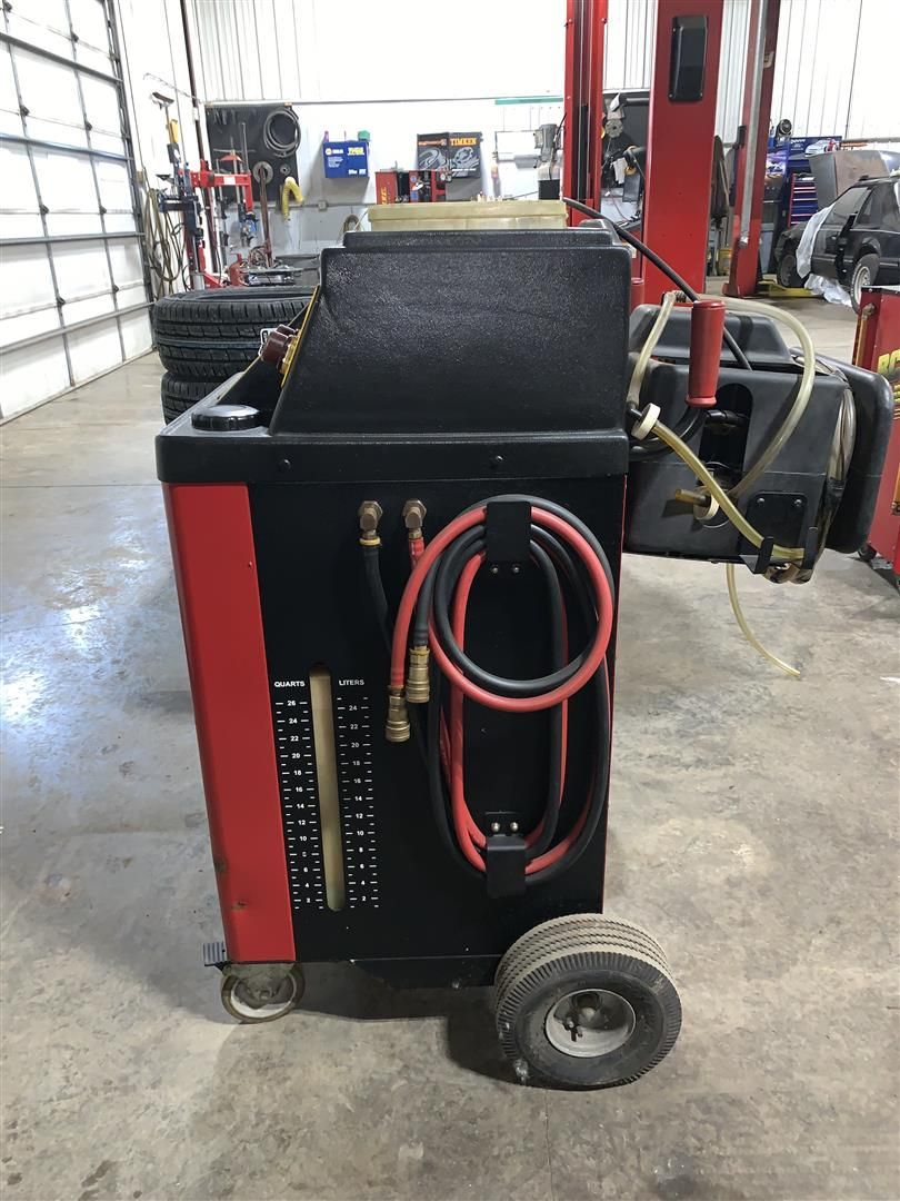 A black and red machine with hose attached to it is in a garage.  | Lou's Car Care Center, Inc.