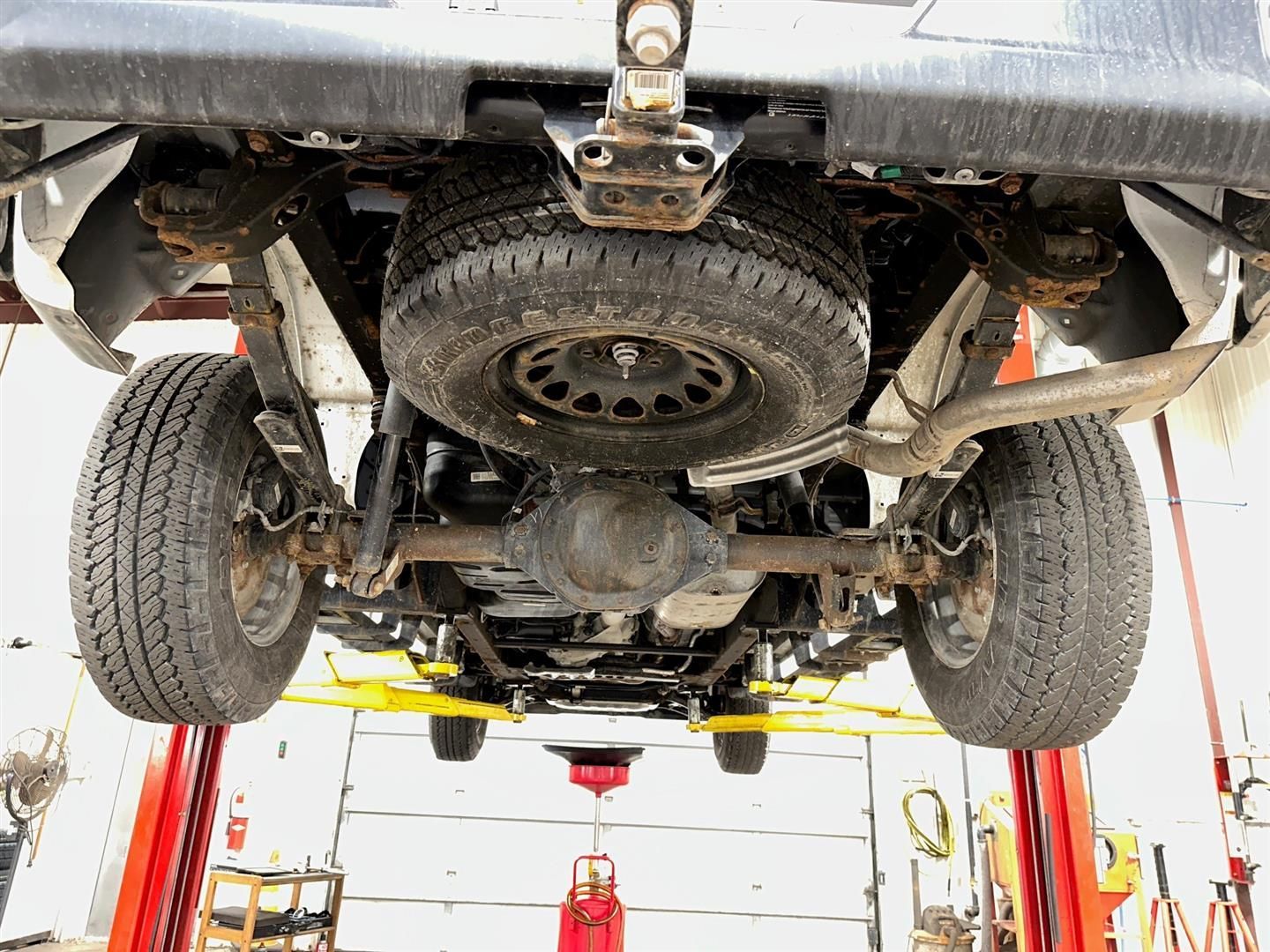 A truck is sitting on a lift in a garage. | Lou's Car Care Center, Inc.