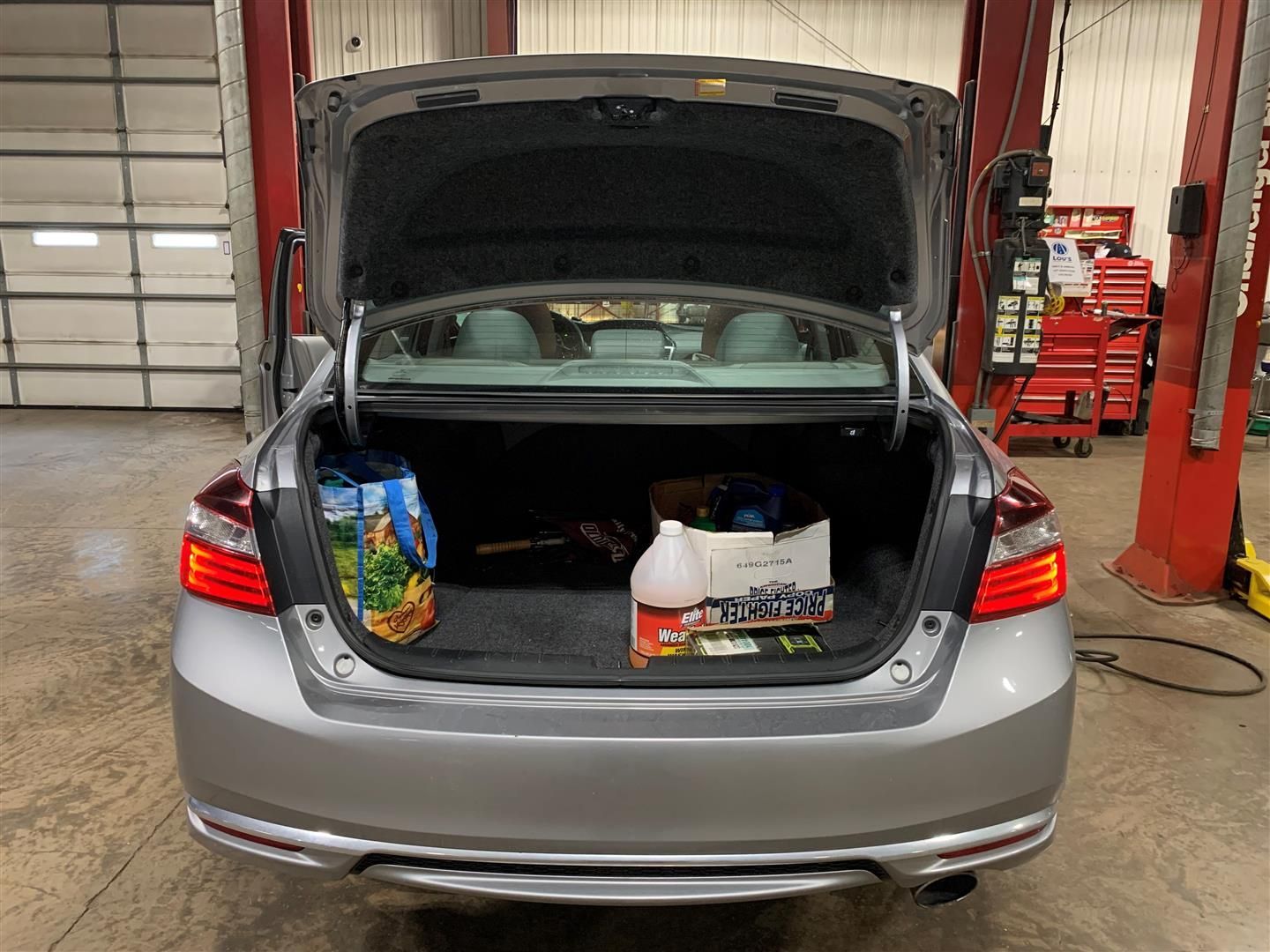 The back of a silver car with the trunk open in a garage. | Lou's Car Care Center, Inc.