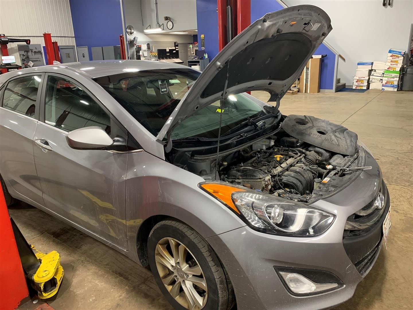 A gray car with its hood up in a garage. | Lou's Car Care Center Inc.