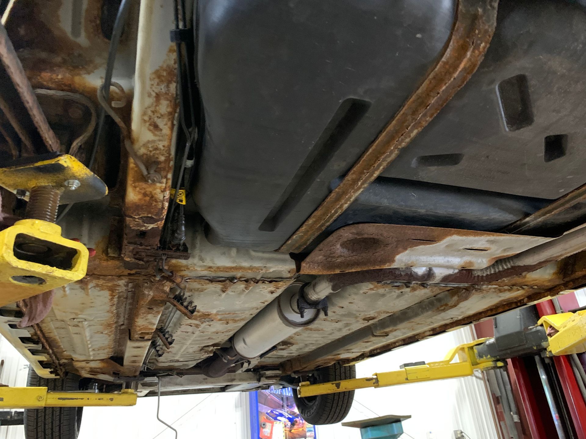 The underside of a car on a lift in a garage  | Lou's Car Care Center Inc.