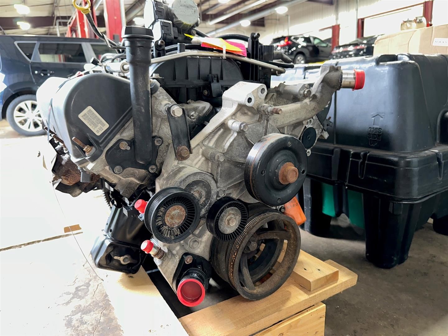 A car engine is sitting on a wooden pallet in a garage. | Lou's Car Care Center, Inc.