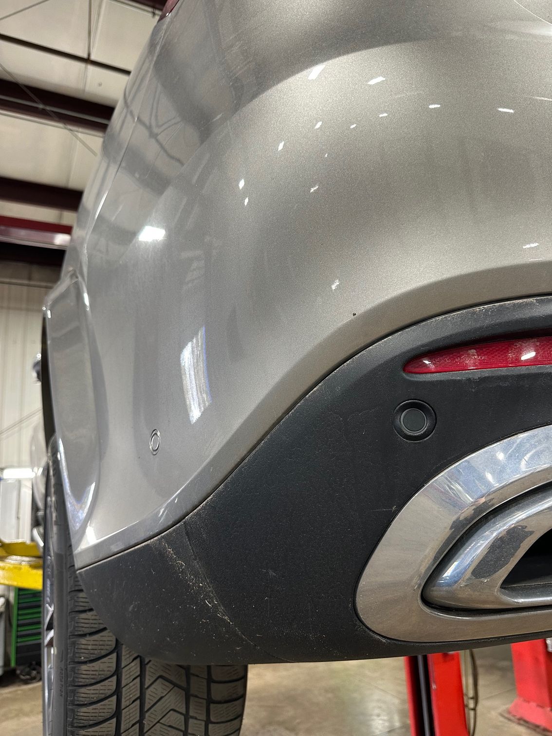 Vehicle ADAS sensors on rear bumper of grey vehicle.