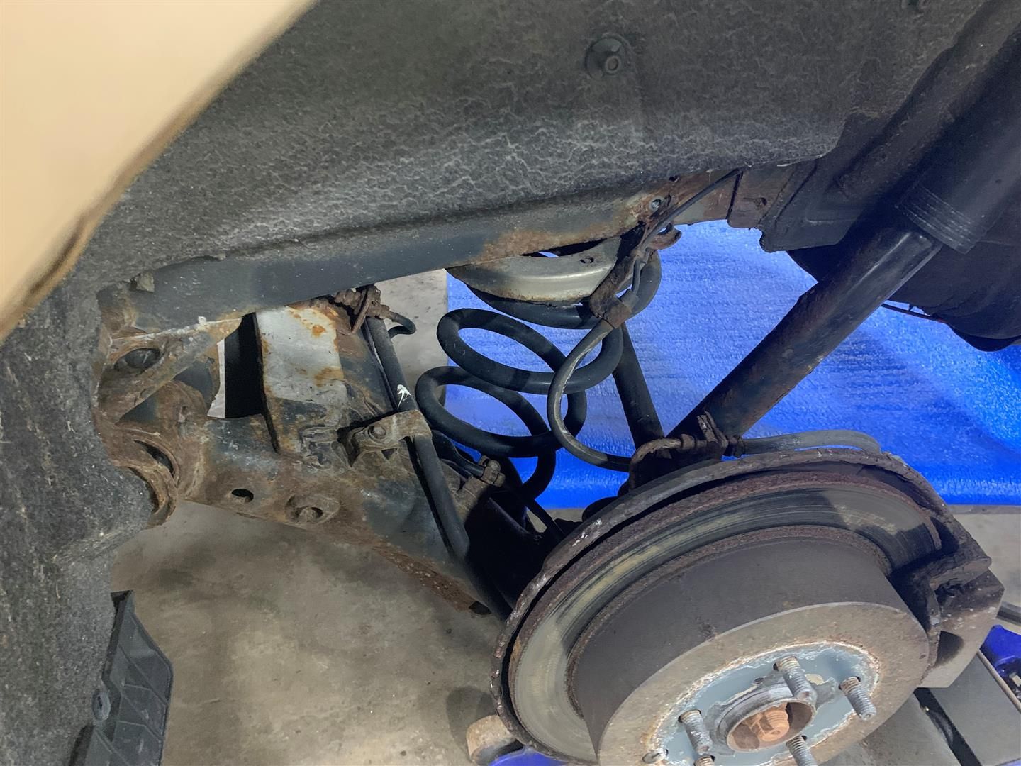 A close up of a car 's rear suspension and brake disc. | Lou's Car Care Center Inc.