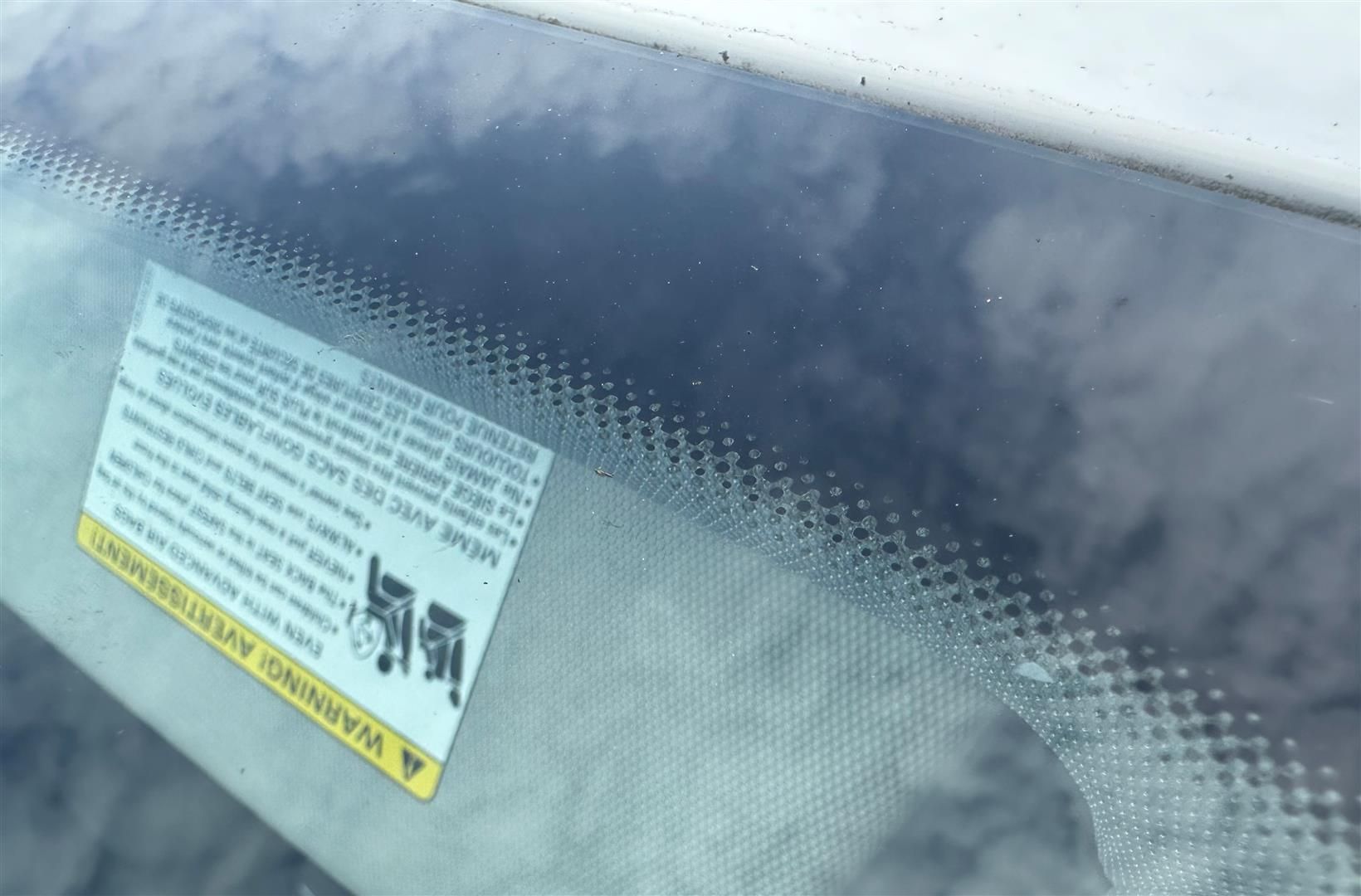 A close up of a windshield with a warning sticker on it. | Lou's Car Care Center, Inc.