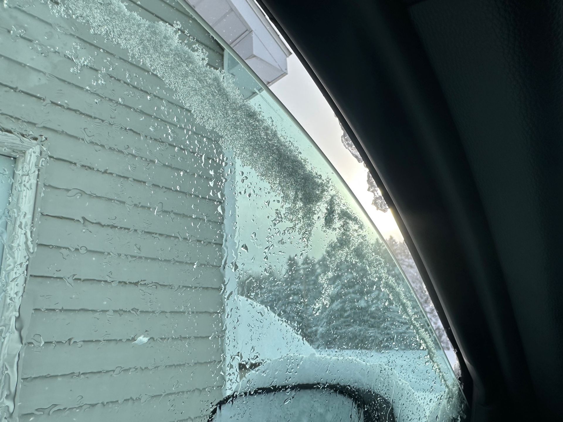 A car windshield with snow on it and a house in the background | Lou's Car Care Center, Inc.