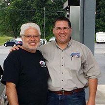 Two men are posing for a picture at a gas station. | Lou's Car Care Center