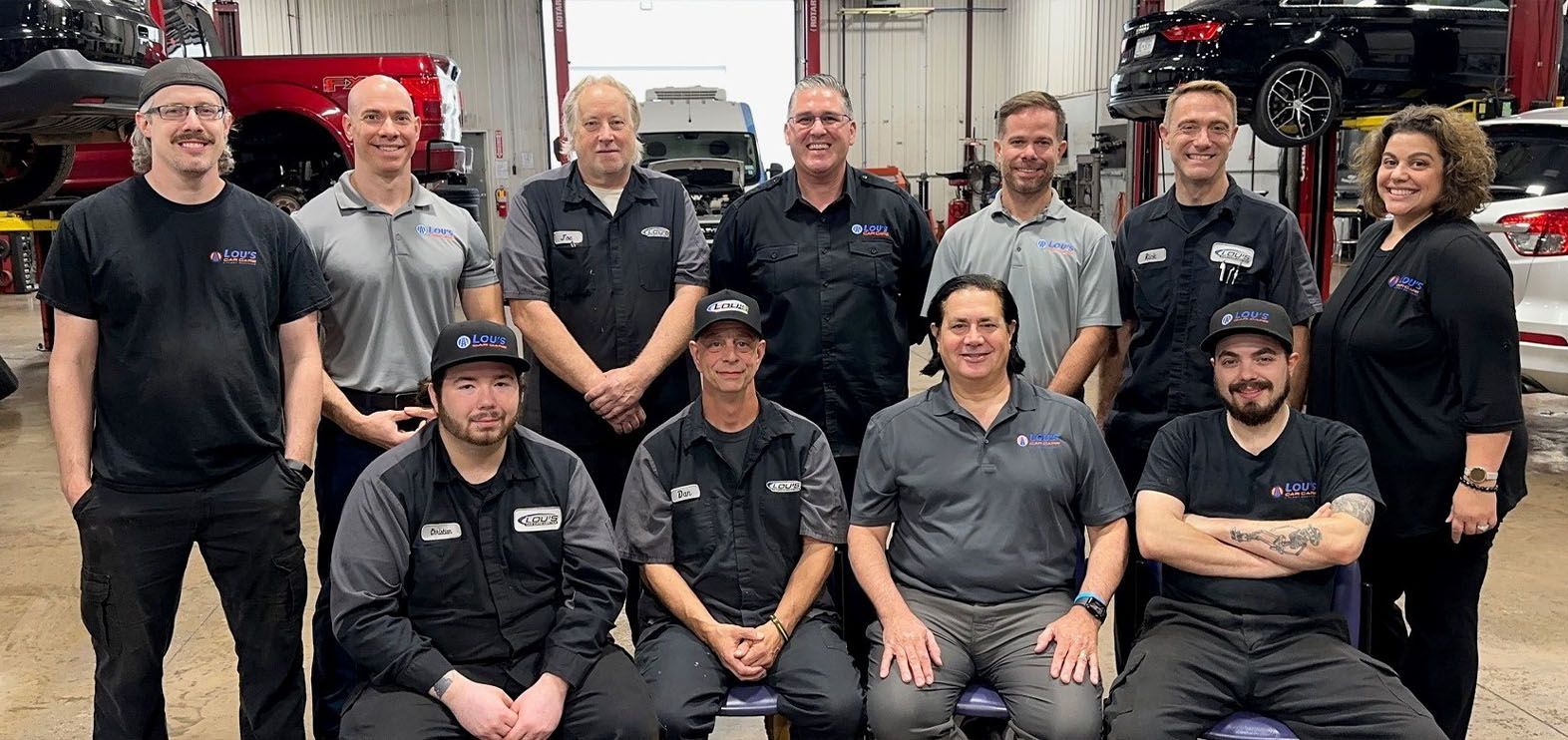 A group of people are posing for a picture in a garage. | Lou's Car Care Center