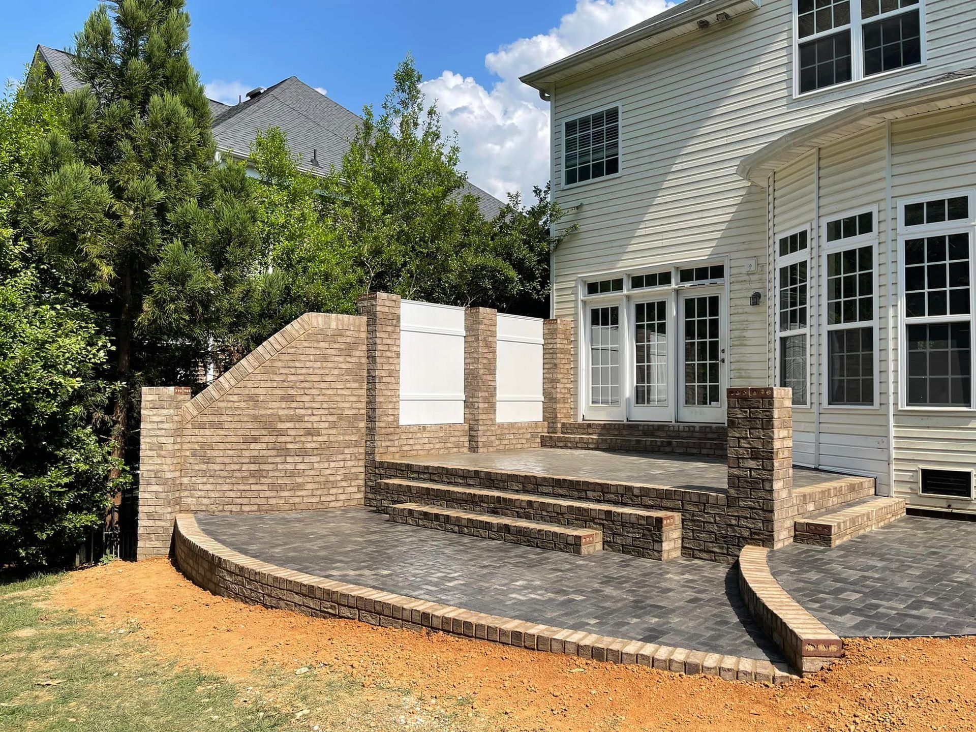 Brick patio with steps leading to a house, brown and gray tones, sunny day.
