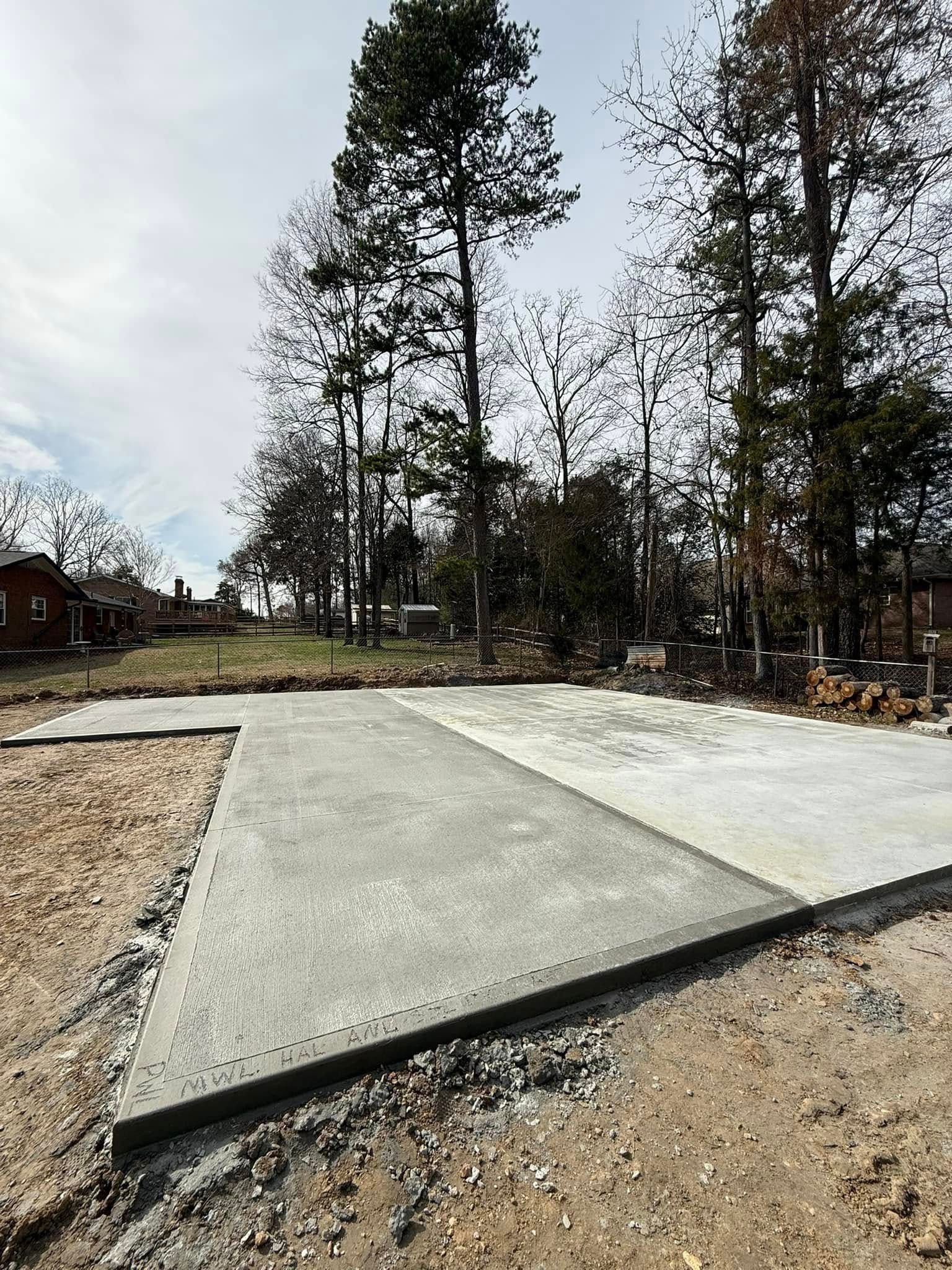 Concrete slab foundation with gravel surround, trees and sky in the background.