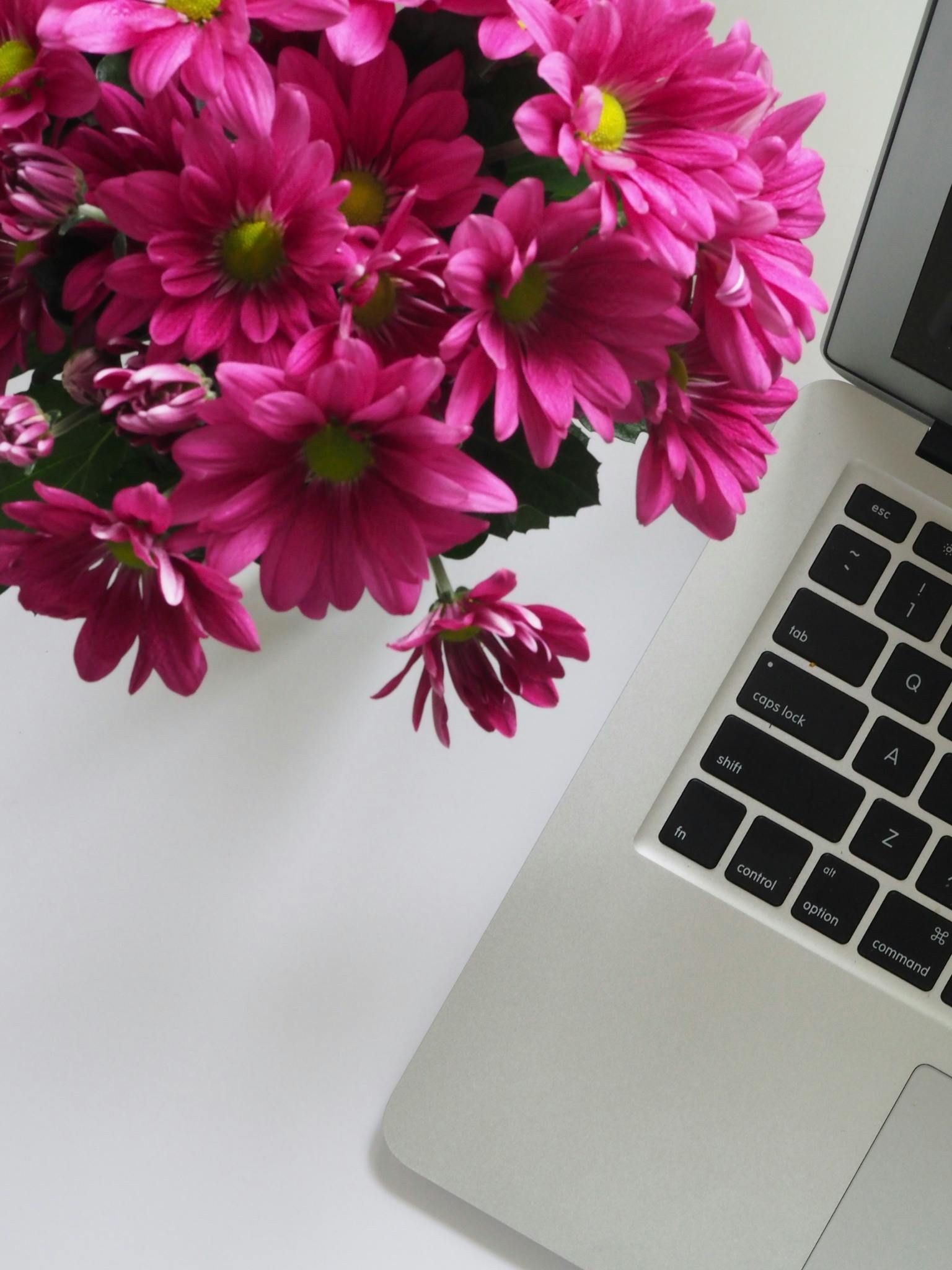 A bunch of pink flowers next to a laptop