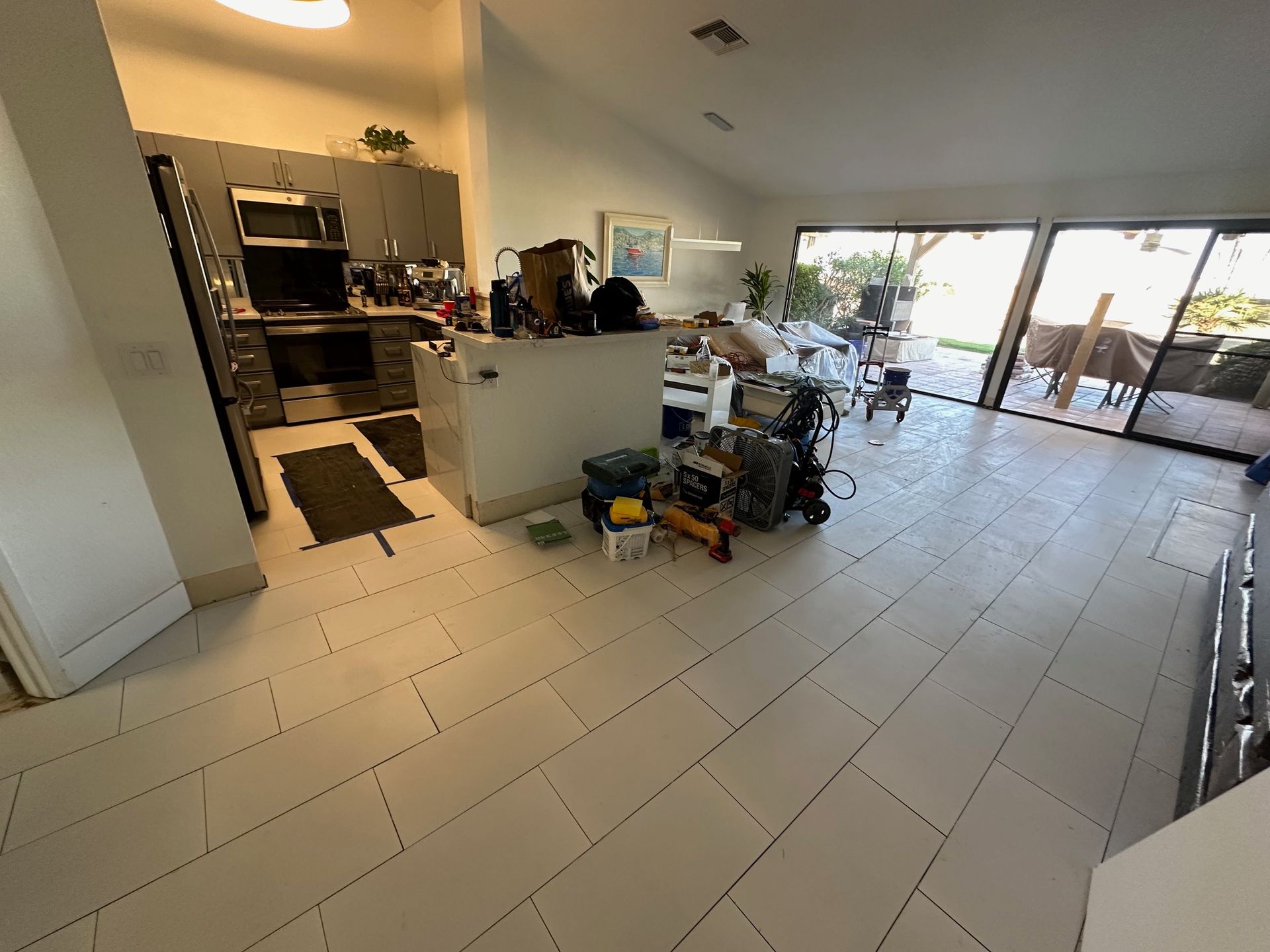 A kitchen with a cluttered counter and open sliding doors leading to an outdoor patio
