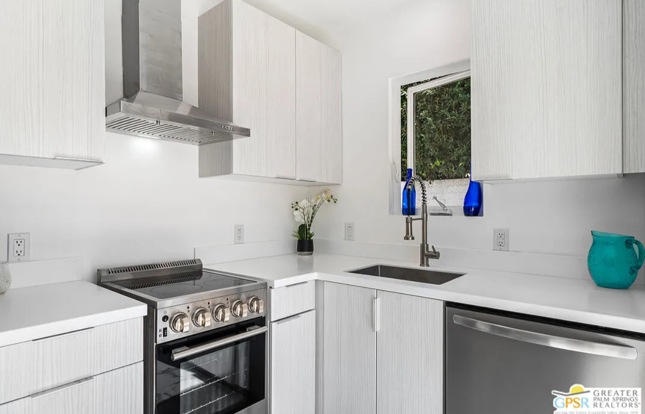 White modern kitchen with stainless steel appliances, white cabinets, and turquoise accents.