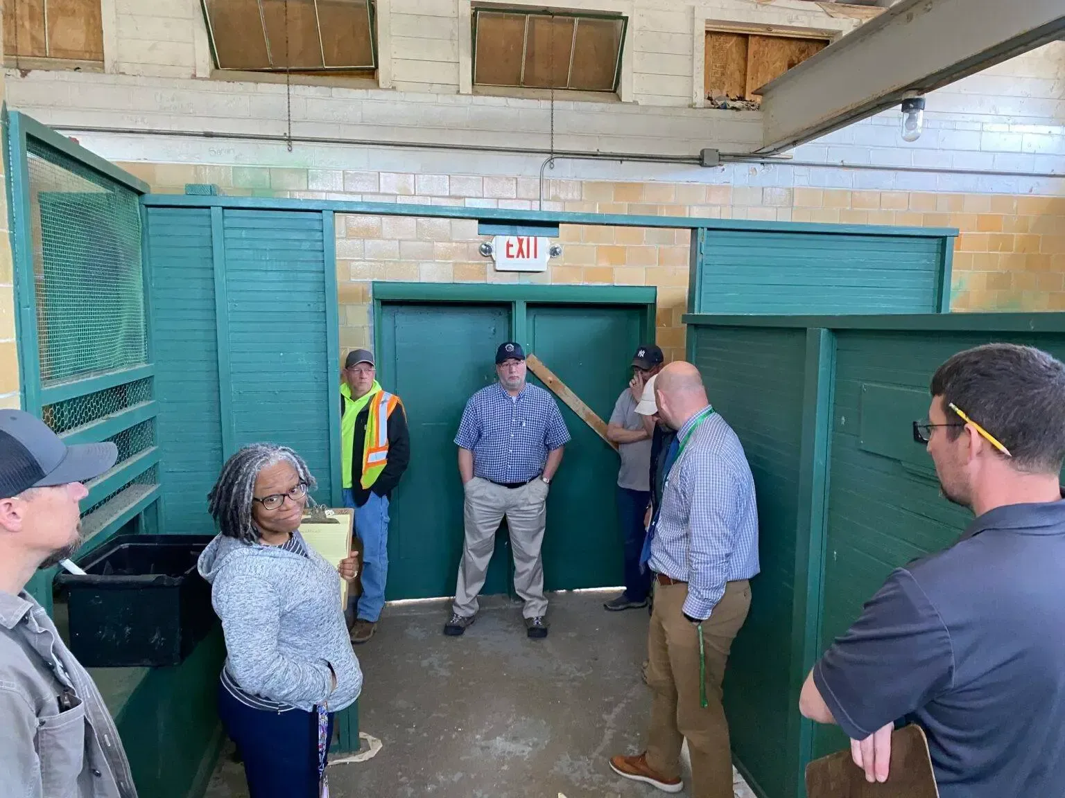 A group of people are standing in a room with green doors.