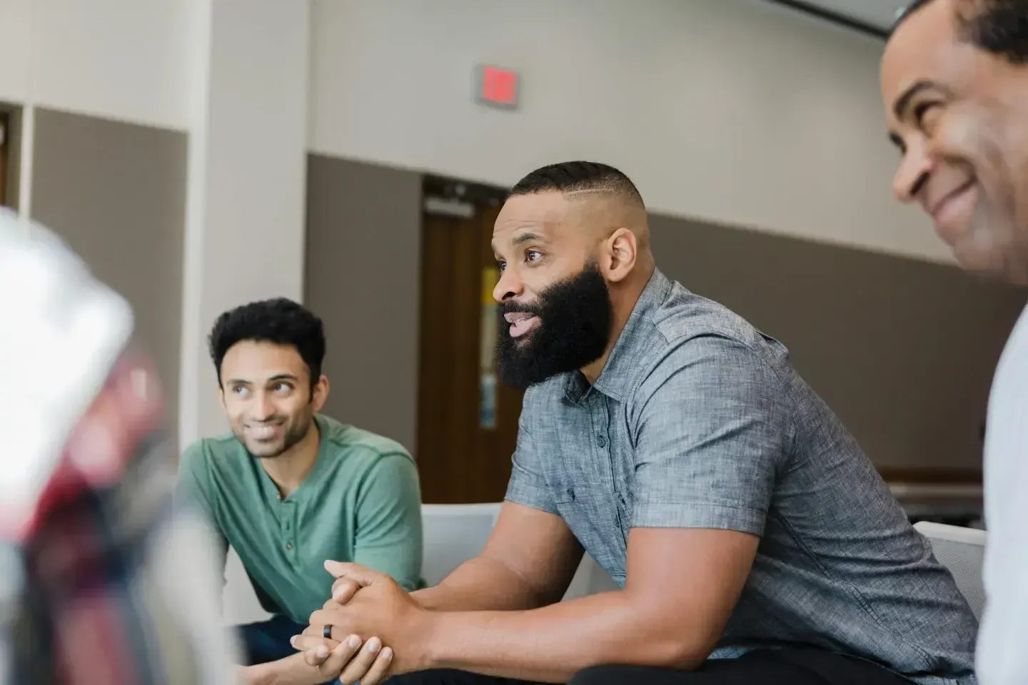 A group of men are sitting around a table having a conversation.