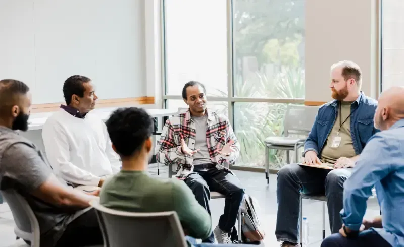 A group of men are sitting in a circle in a room.