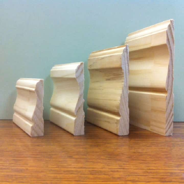 Four wooden baseboards of increasing size, displayed on a wood surface, against a pale green wall.