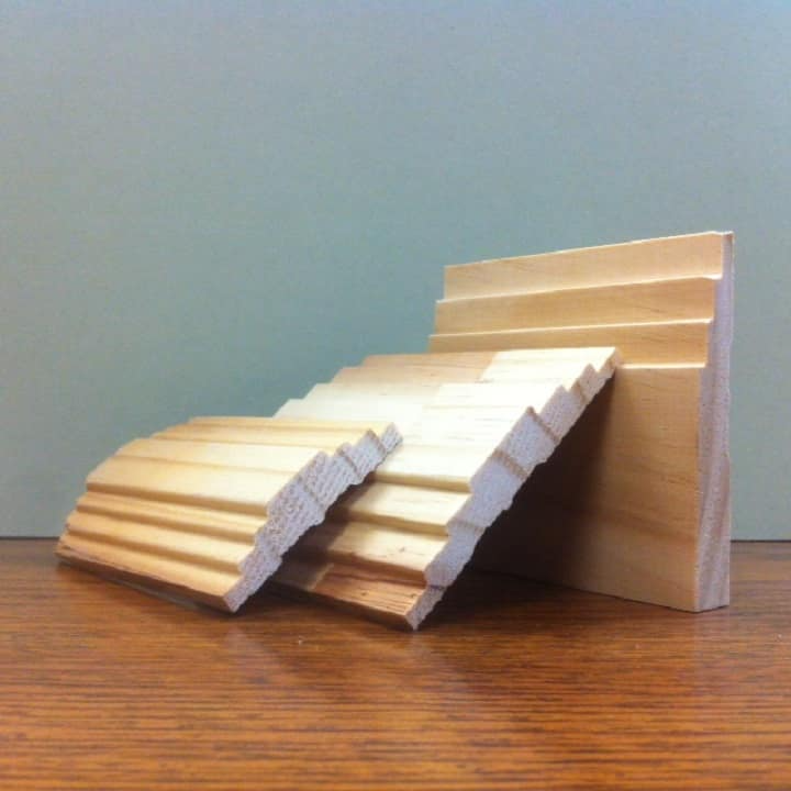 Three wooden molding samples in various shapes on a wooden surface.