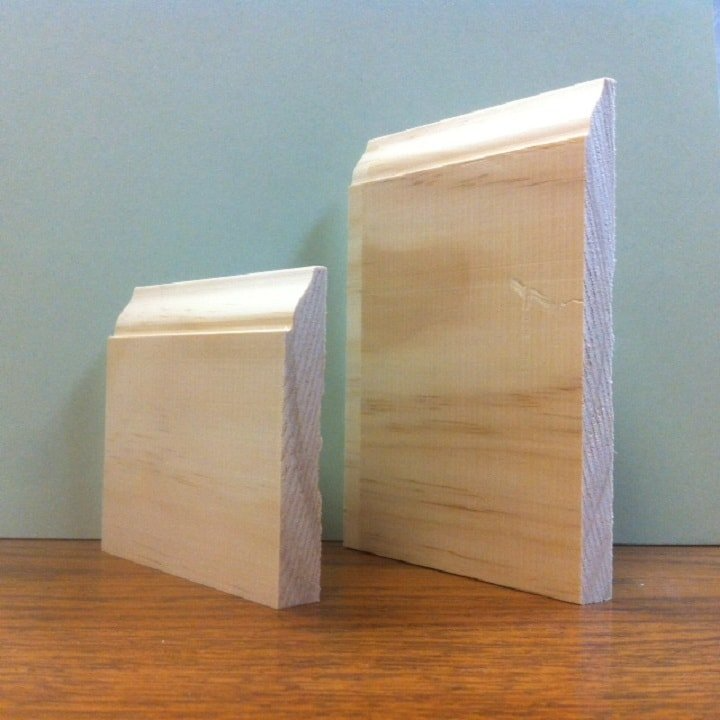 Two pieces of unfinished wooden baseboard trim with a curved top, on a wooden surface.