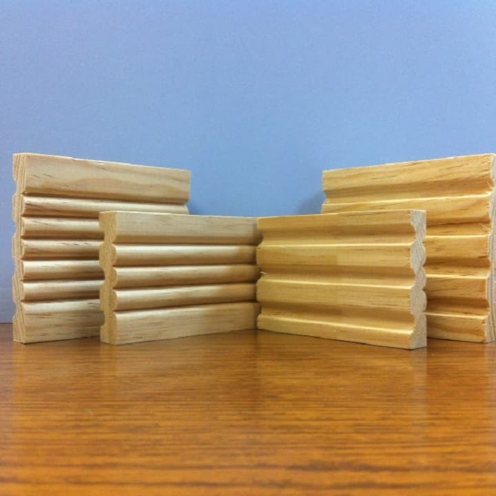 Wooden decorative molding pieces on a table, with a blue background.