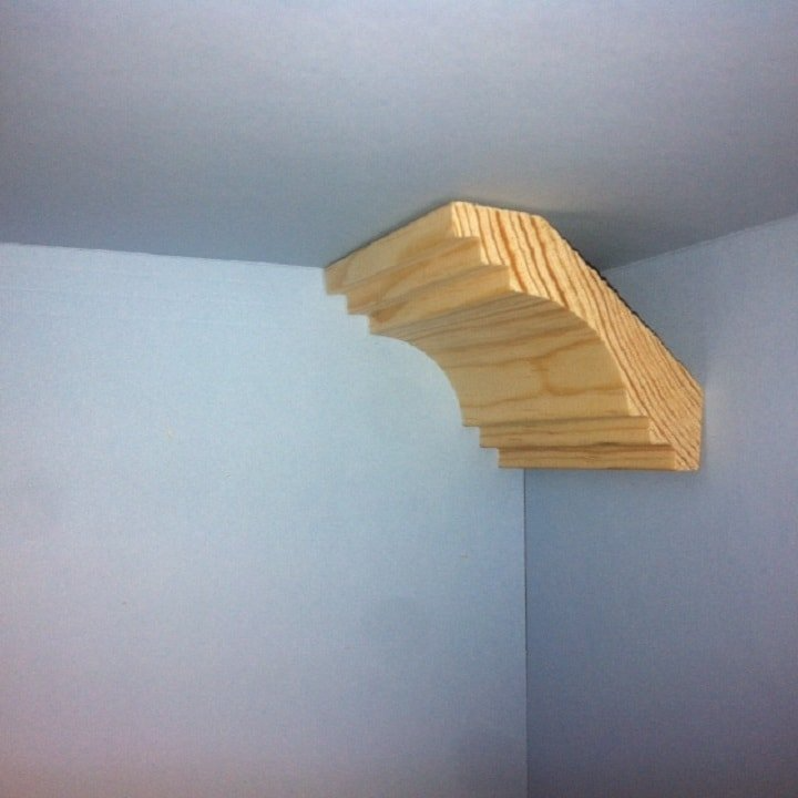 Wooden crown molding corner piece against blue walls.