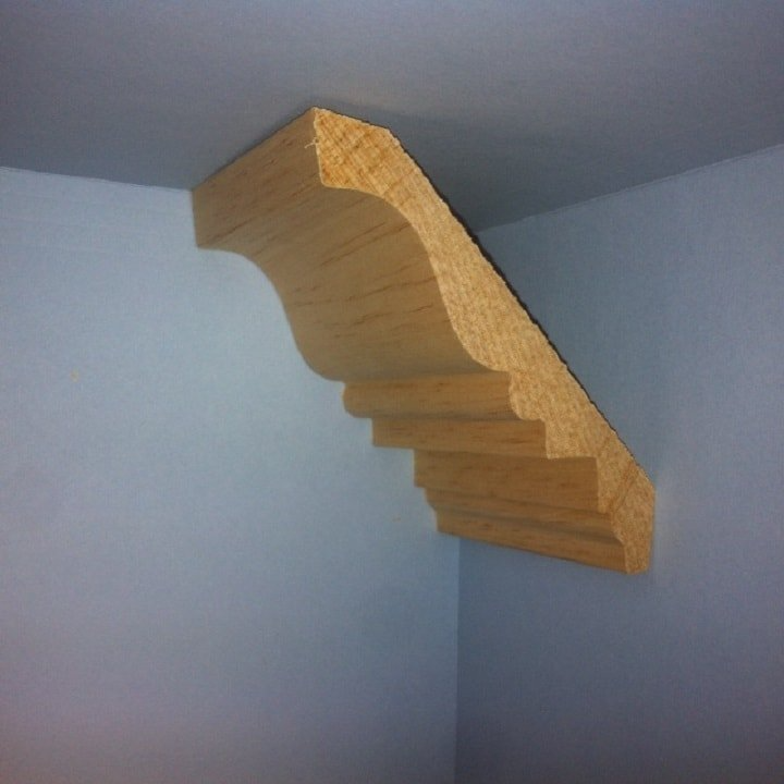 Wooden crown molding installed in a corner where the wall meets the ceiling.