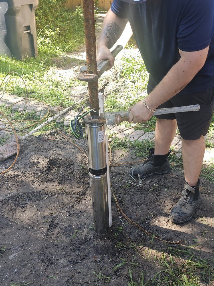 Man installing a submersible well pump in an outdoor setting.