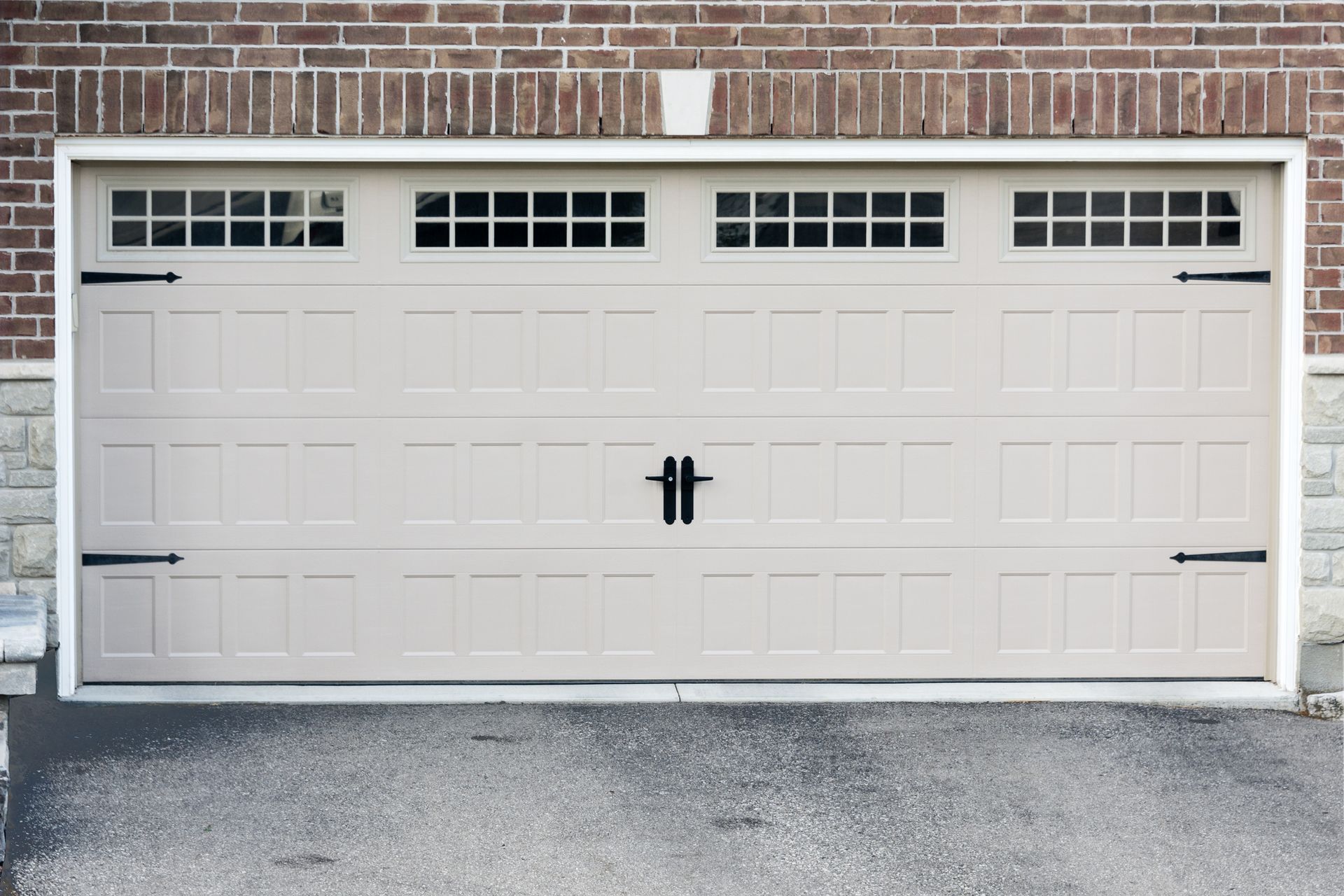 A white garage door is sitting in front of a brick building.