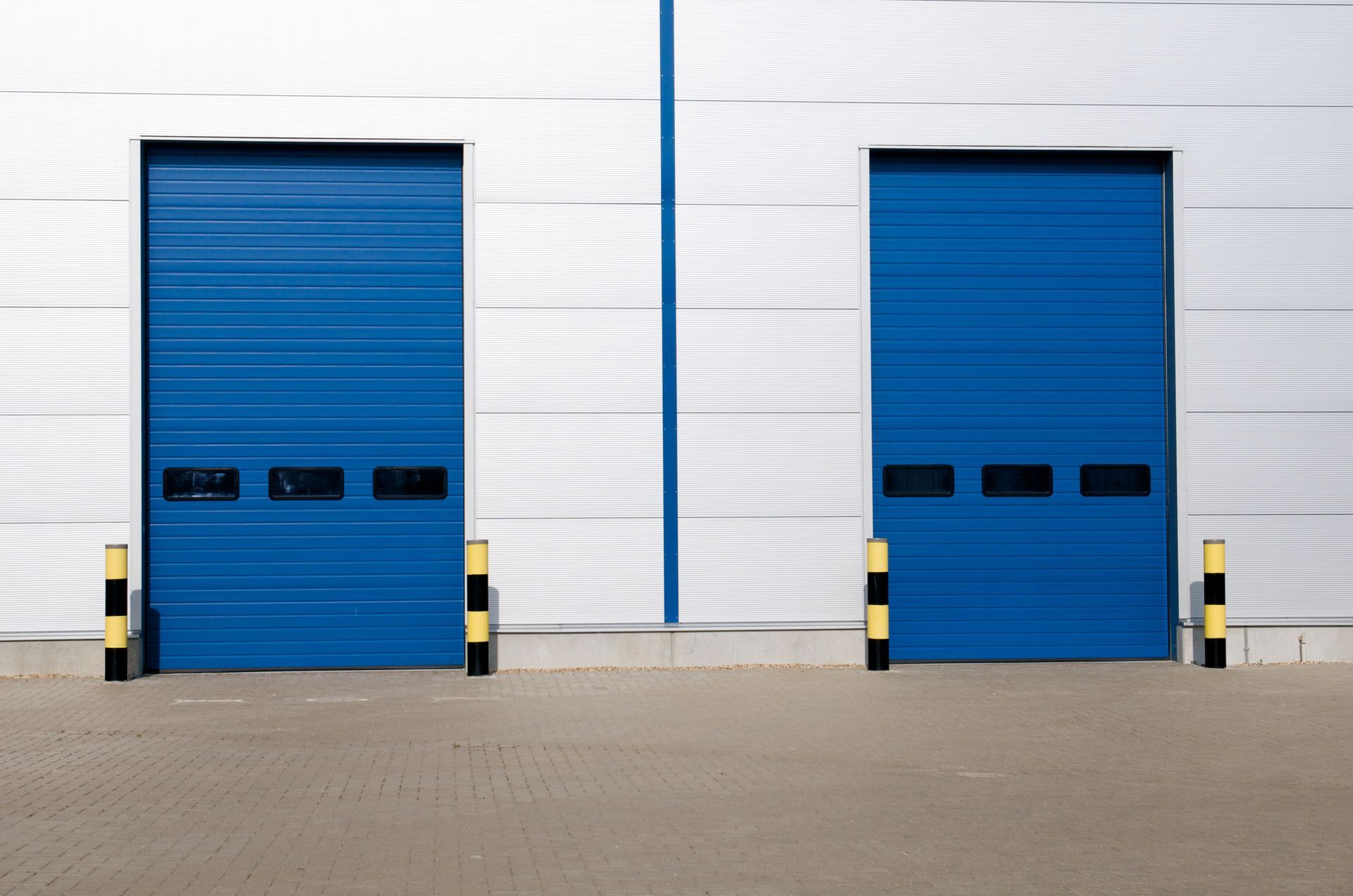 Two blue garage doors are on the side of a building.