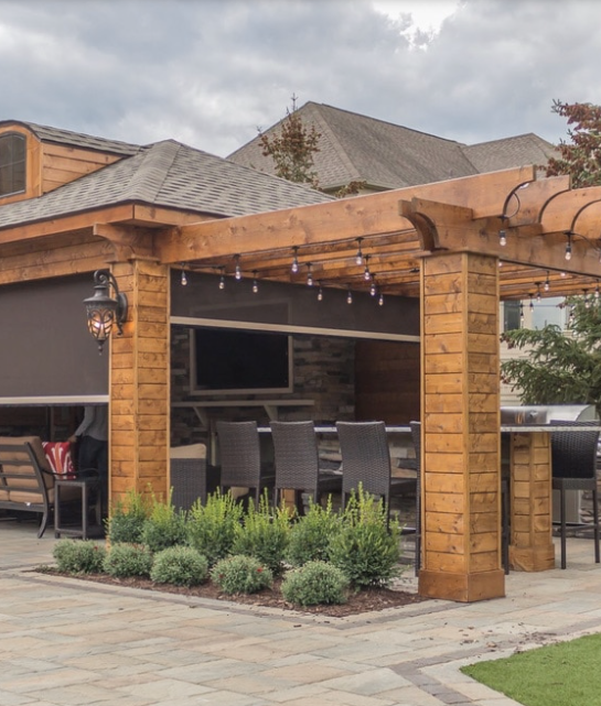 A wooden pergola with a dining table and chairs underneath it