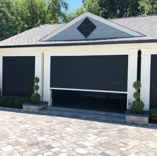 A white house with black shutters on the garage doors