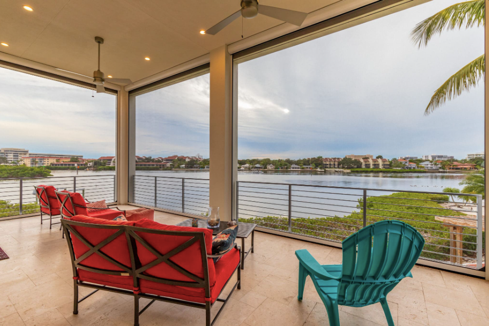 A patio with a view of a lake and a couch and chairs.