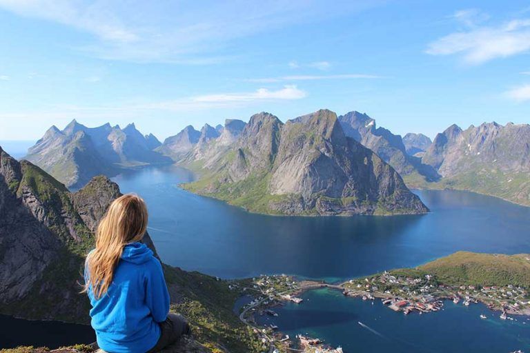 woman on mountain top looking down at hills and water taking next steps to calm travel anxiety