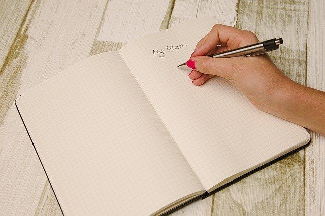 woman's hand writing in journal on page that says my plan to get things done despite anxiety