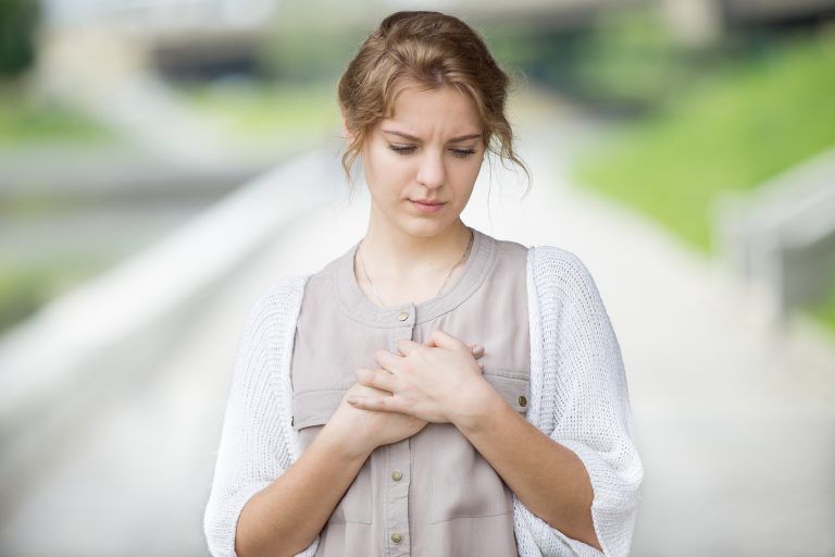 Woman with hand on her heart because of anxiety symptoms